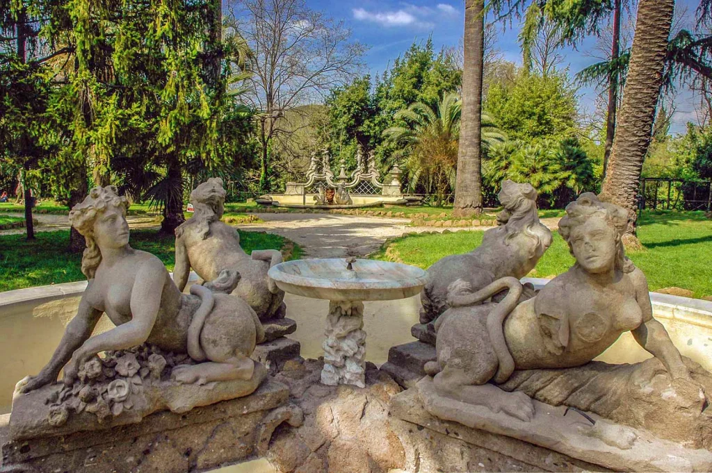 Stone nymph sculptures around a fountain in Villa Sciarra, surrounded by greenery in a historic Roman garden