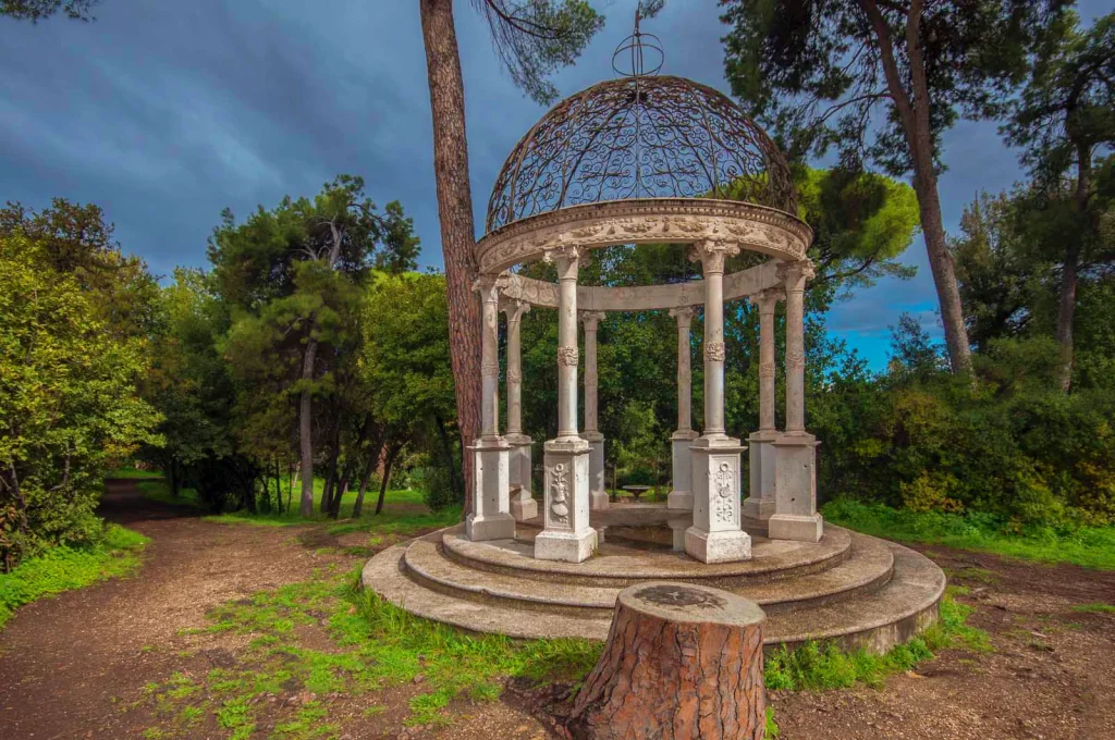Neoclassical tempietto surrounded by trees in Villa Sciarra, Rome, during an eco-friendly walking tour.